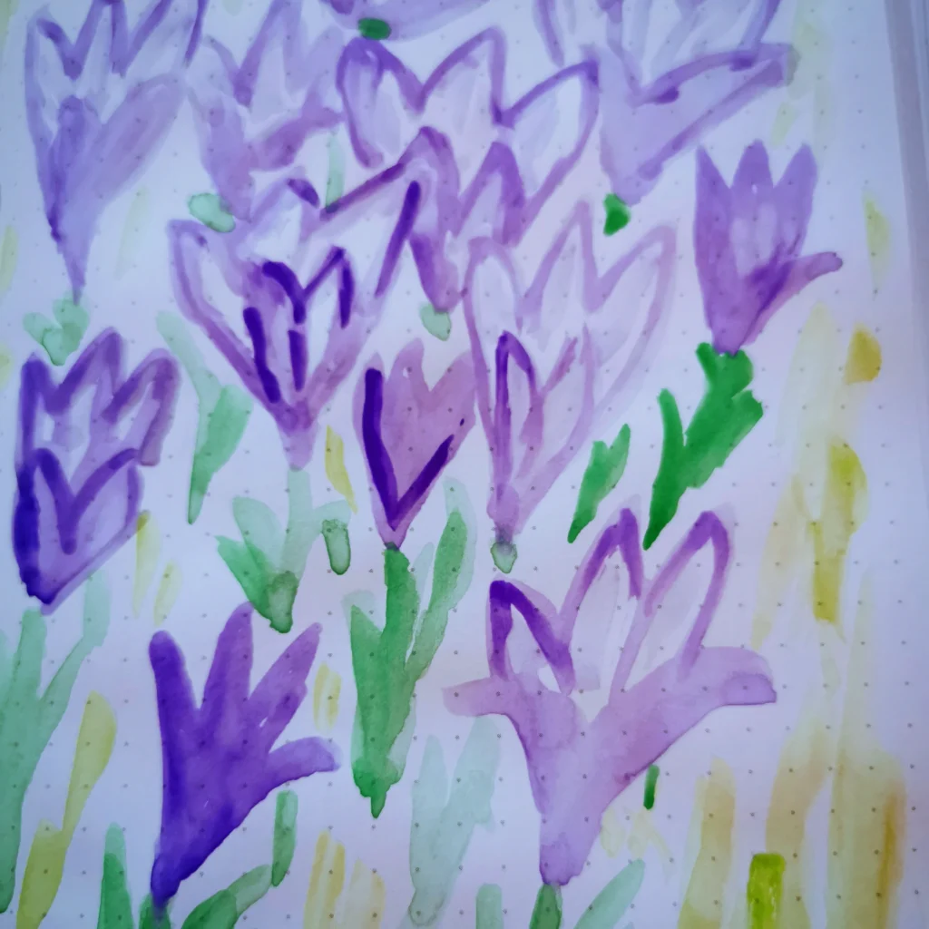 Das Bild zeigt zarte, lila Blüten inmitten frischen Grüns. Weiche, aquarellartige Gelb- und Grüntöne im Hintergrund. 